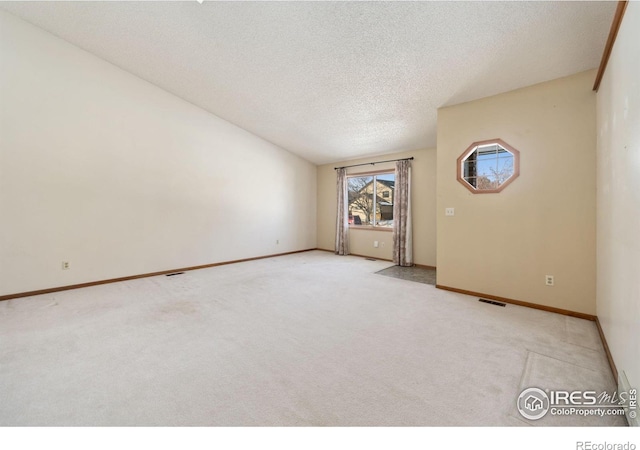 carpeted empty room with lofted ceiling and a textured ceiling