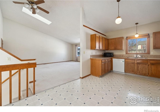 kitchen with sink, lofted ceiling with skylight, white dishwasher, decorative light fixtures, and light colored carpet