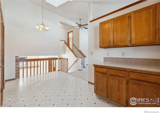 kitchen with decorative light fixtures, a skylight, and ceiling fan with notable chandelier