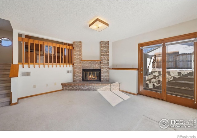 unfurnished living room featuring light colored carpet, a brick fireplace, and a textured ceiling