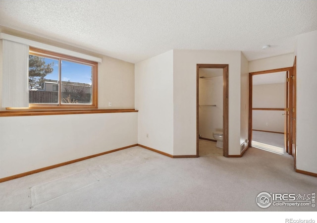 spare room featuring light carpet and a textured ceiling