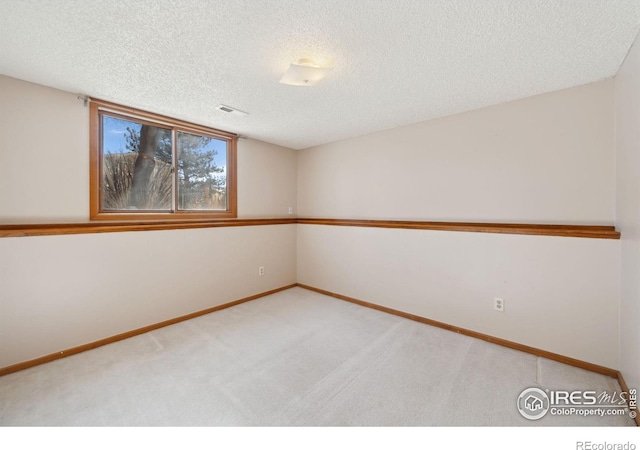 carpeted empty room featuring a textured ceiling