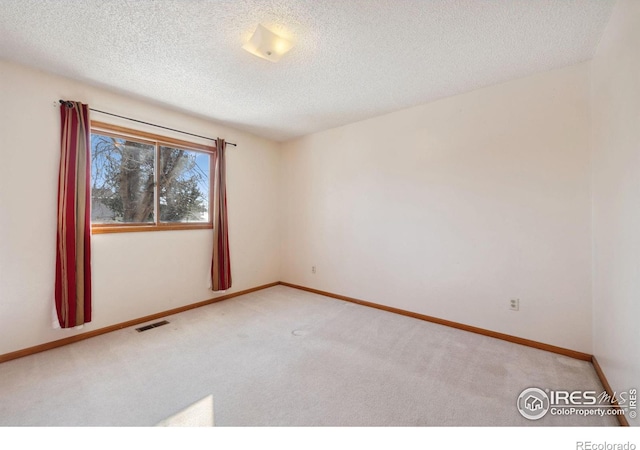 empty room featuring light carpet and a textured ceiling