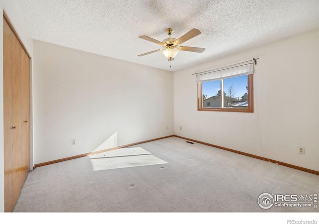 spare room featuring light colored carpet, a textured ceiling, and ceiling fan