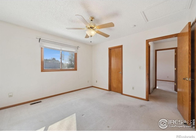 unfurnished bedroom with light carpet, ceiling fan, and a textured ceiling