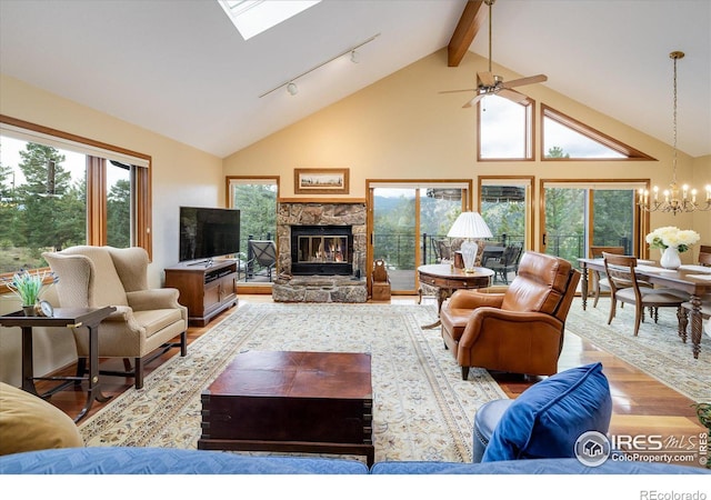 living room with a stone fireplace, high vaulted ceiling, light wood-type flooring, a notable chandelier, and beamed ceiling