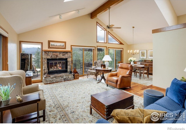 living room featuring hardwood / wood-style floors, beam ceiling, high vaulted ceiling, a fireplace, and ceiling fan with notable chandelier