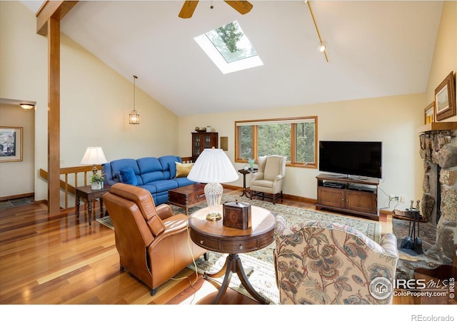 living room featuring a skylight, high vaulted ceiling, ceiling fan, and light wood-type flooring