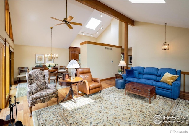 living room with ceiling fan with notable chandelier, high vaulted ceiling, a skylight, beamed ceiling, and light hardwood / wood-style floors