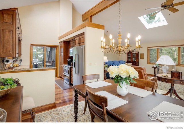 dining area featuring an inviting chandelier, a skylight, high vaulted ceiling, light hardwood / wood-style flooring, and beam ceiling