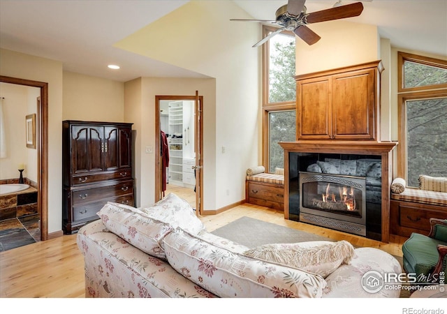 living room with ceiling fan, vaulted ceiling, and light wood-type flooring