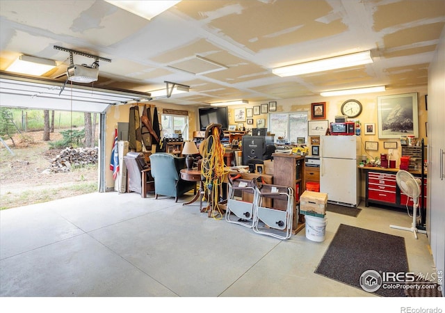 garage featuring a garage door opener, a workshop area, and white fridge