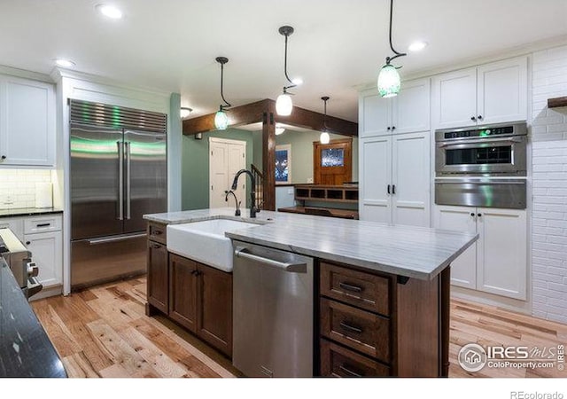 kitchen featuring white cabinetry, stainless steel appliances, sink, and hanging light fixtures