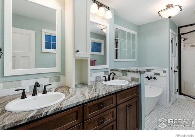 bathroom with tile patterned flooring, vanity, a tub, and tile walls