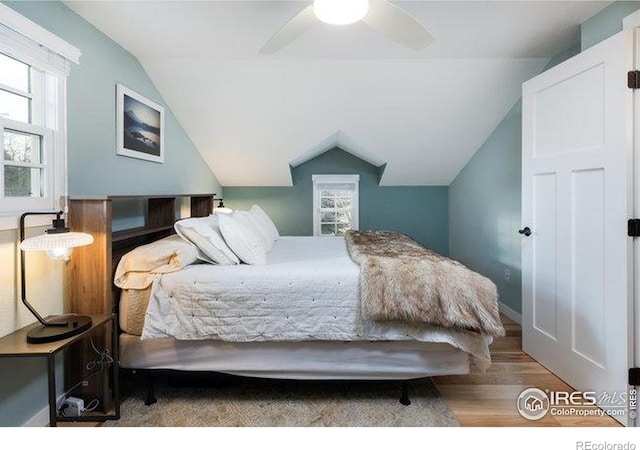 bedroom with hardwood / wood-style flooring, ceiling fan, vaulted ceiling, and multiple windows