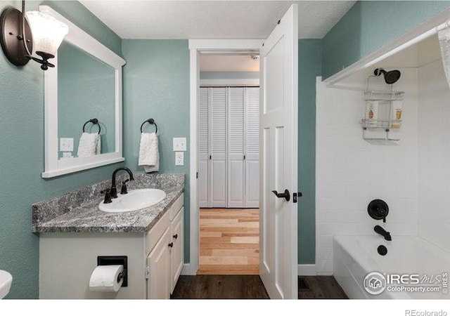 bathroom with hardwood / wood-style flooring, vanity, and tiled shower / bath combo