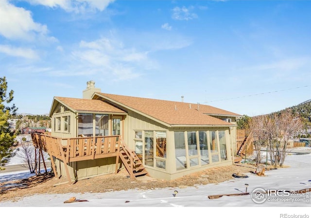 snow covered property with a deck and a sunroom