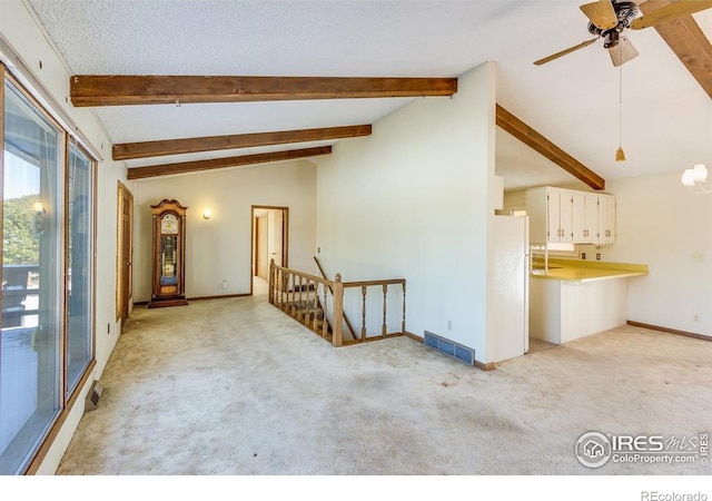 unfurnished living room featuring ceiling fan, lofted ceiling with beams, light colored carpet, and a textured ceiling