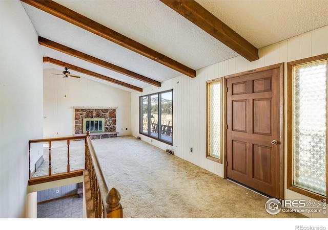 carpeted foyer featuring a fireplace, lofted ceiling with beams, wooden walls, and a textured ceiling