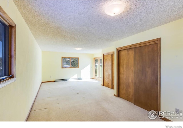 carpeted empty room with baseboard heating and a textured ceiling