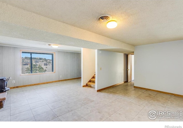 basement with light tile patterned floors, a textured ceiling, and a wood stove