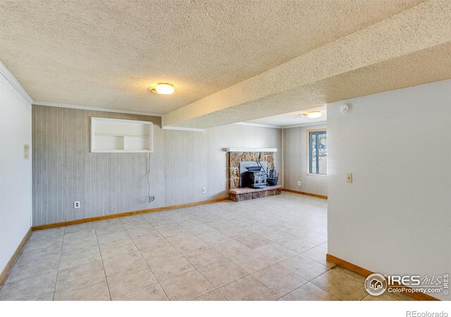 unfurnished living room featuring tile patterned flooring, wooden walls, built in features, and a textured ceiling