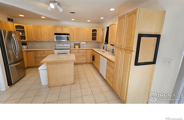 kitchen with sink, a center island, light tile patterned floors, light brown cabinets, and stainless steel appliances