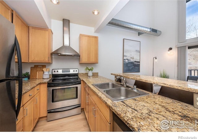 kitchen with wall chimney range hood, sink, black refrigerator, electric range, and kitchen peninsula