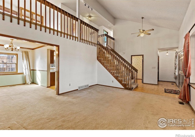 unfurnished living room with light carpet, ceiling fan with notable chandelier, and a towering ceiling