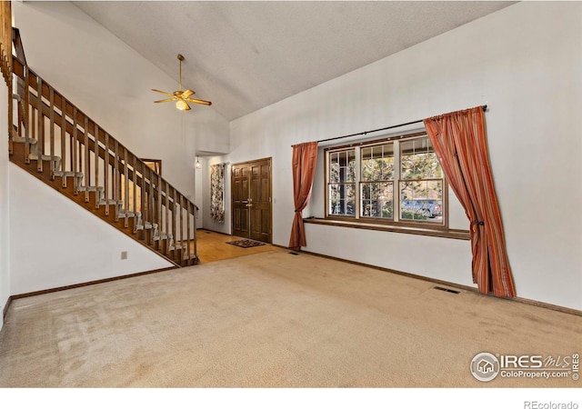 unfurnished living room featuring high vaulted ceiling, ceiling fan, and carpet flooring