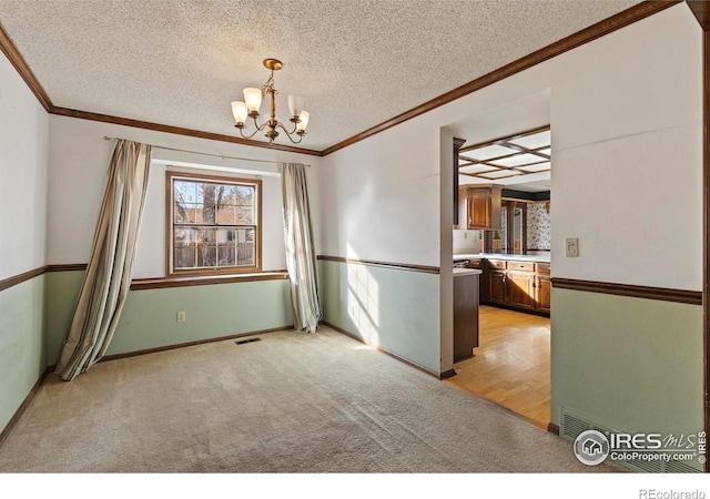 unfurnished room with light colored carpet, ornamental molding, a chandelier, and a textured ceiling