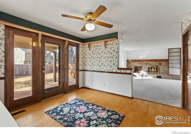 interior space with a brick fireplace, light hardwood / wood-style floors, and a textured ceiling