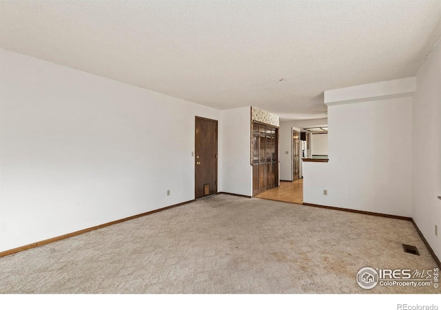 unfurnished living room featuring light carpet and a textured ceiling