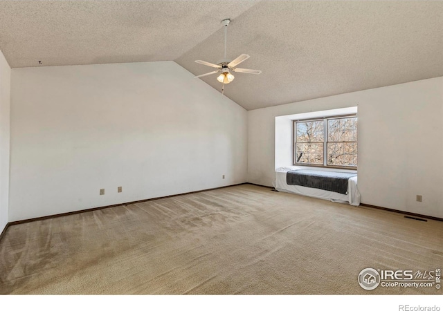 unfurnished living room with a textured ceiling, vaulted ceiling, light colored carpet, and ceiling fan