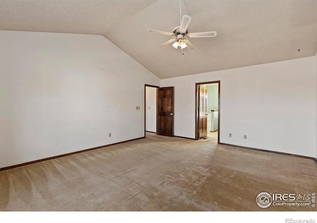 carpeted spare room with lofted ceiling, a textured ceiling, and ceiling fan