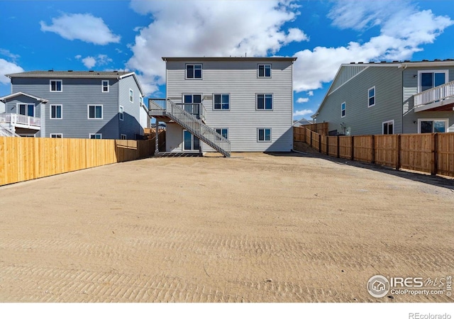 back of property with stairway and a fenced backyard