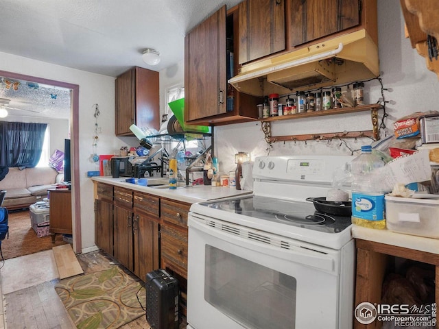 kitchen featuring sink, white electric range, a textured ceiling, and light hardwood / wood-style floors