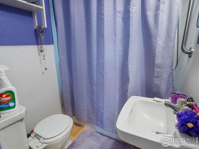 bathroom with tile walls, sink, toilet, and a shower with shower curtain