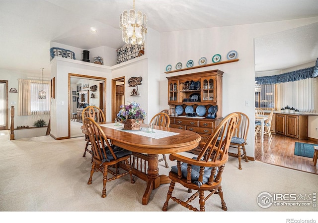 dining area with light colored carpet and a notable chandelier