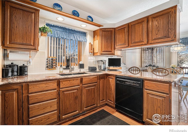 kitchen featuring dishwasher, sink, decorative backsplash, kitchen peninsula, and light stone countertops