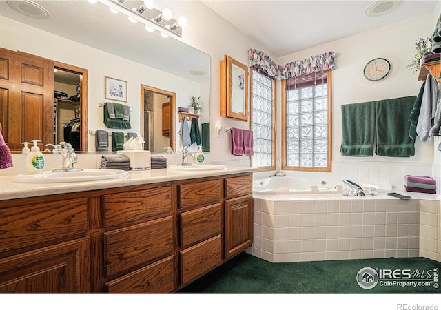 bathroom with tiled tub and vanity