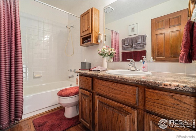 full bathroom featuring hardwood / wood-style flooring, vanity, shower / bath combination with curtain, and toilet