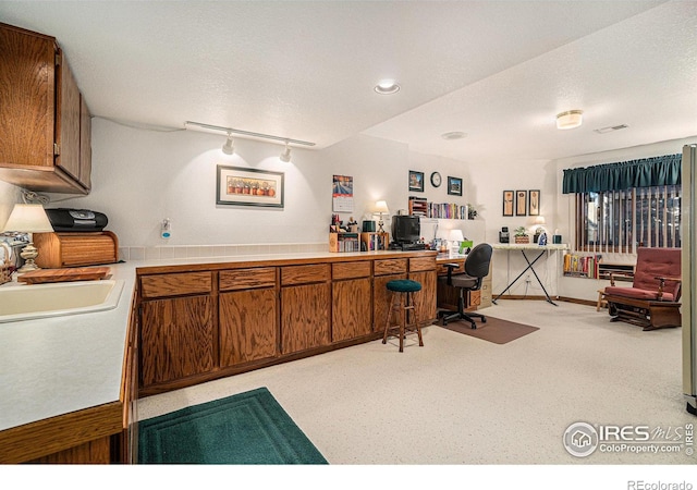 home office featuring sink, rail lighting, and a textured ceiling