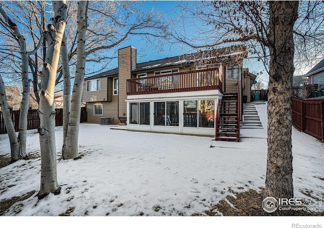 snow covered house featuring a sunroom and central air condition unit