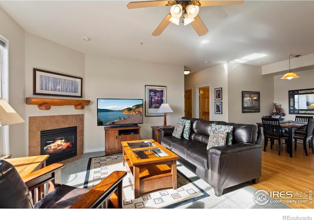 living room with a tile fireplace and light wood-type flooring