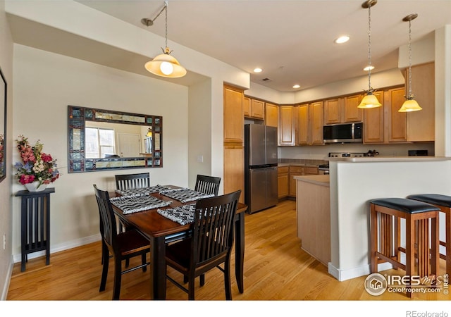 kitchen featuring pendant lighting, stainless steel appliances, kitchen peninsula, and light hardwood / wood-style floors