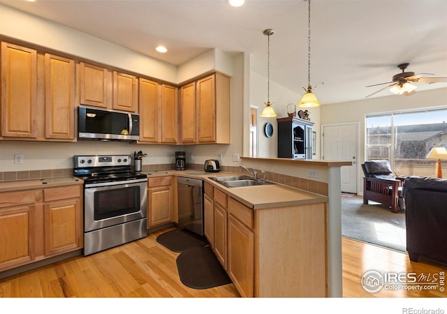 kitchen with sink, hanging light fixtures, light hardwood / wood-style flooring, appliances with stainless steel finishes, and kitchen peninsula