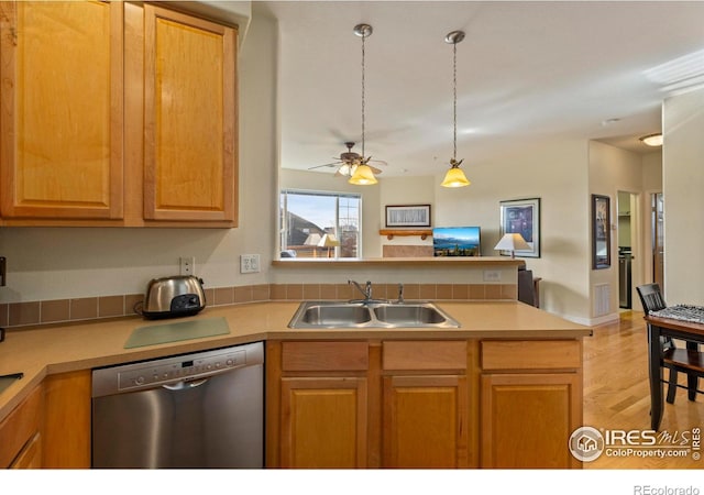 kitchen with sink, light hardwood / wood-style flooring, decorative light fixtures, stainless steel dishwasher, and kitchen peninsula