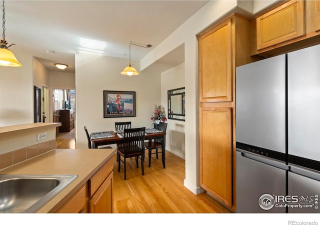 kitchen featuring sink, hanging light fixtures, and light hardwood / wood-style flooring