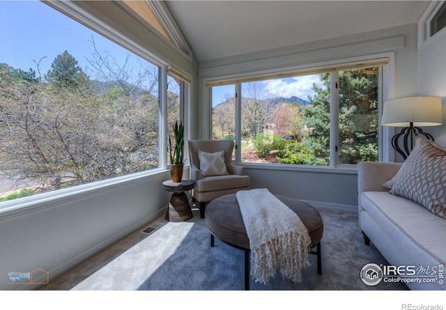 sunroom / solarium with lofted ceiling, visible vents, a mountain view, and a wealth of natural light